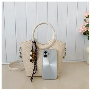 Sac crème tressé, poignée ronde, perles en bois et bandoulière amovible, près d’un téléphone