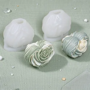 White rose silicone molds beside two finished rose-shaped pieces on a pale green grid surface