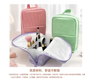 Open purple-striped bag shows makeup brushes beside red and green striped bags on a white table