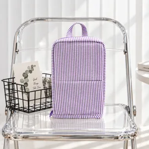 Purple and white striped quilted zippered bag with a top handle, displayed on a clear chair