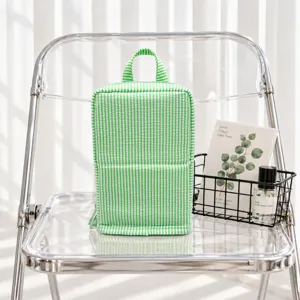 Green-and-white striped fabric bag with a top handle and zipper, displayed on a clear chair