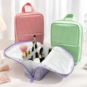 Open striped organizer shows elastic brush loops and clear pockets, with red and green bags behind