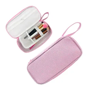 Offen und geschlossen: rosa Streifenstoff mit Netzeinteilung und Haltern für Make-up-Pinsel.
