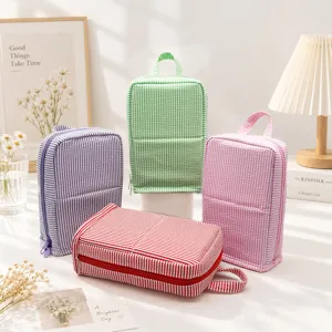 Four purple, green, pink and red striped seersucker pouches arranged on a bright tabletop