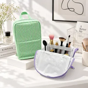Green striped seersucker toiletry bag beside a clear makeup pouch with purple trim and brush slots