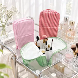 Striped bags in pink, red and green; the open green one shows clear lining and brush compartments
