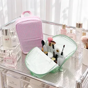 Two striped toiletry bags on a vanity, with a clear inner pocket and divided brush compartments