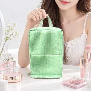 Green-and-white striped fabric bag held upright on a vanity beside perfume and makeup items