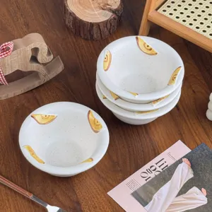 Bovenaanzicht van matte witte keramische schaaltjes met handgeschilderde bananen op een houten tafel