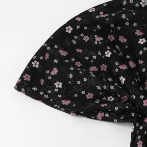 Dettaglio del tessuto nero leggero con stampa floreale rosa e bianca e pieghe ben visibili