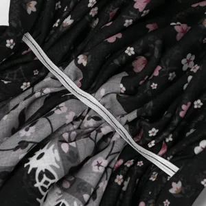 Primo piano del tulle nero a fiori, delle parti stampate grigie e del nastro bianco arricciato