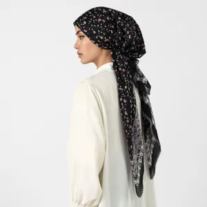 Vista laterale di una modella con un foulard nero decorato con piccoli fiori rosa e bianchi