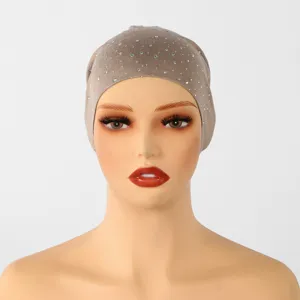 Vooraanzicht van een taupe gebreide muts op een mannequin, met kleine zilveren strasssteentjes