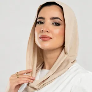 Primo piano di una donna con un morbido foulard beige avvolto intorno alla testa e al collo