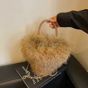 Close-up of a brown heart-shaped faux-fur bag with braided handle and gold chain on a book