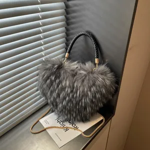 Heart-shaped shaggy bag with a black braided handle and gold chain, displayed beside a window