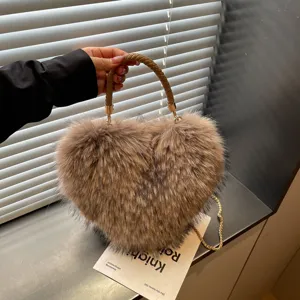 Close-up detail of a brown faux-fur heart bag with woven handle and gold chain strap