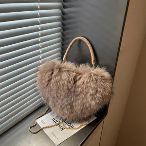 Brown heart-shaped bag with fluffy texture, braided handle and gold chain, shown beside a window