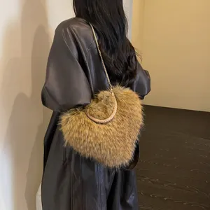 Model carrying a brown plush shoulder bag with a gold chain strap and braided handle