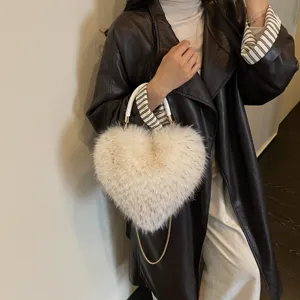 A cream fluffy heart-shaped bag with a gold chain is styled over a dark leather coat.