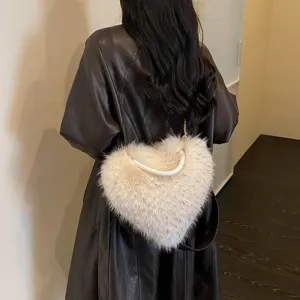 Back view of a model carrying a fluffy ivory heart-shaped bag with a white rope handle and gold chain