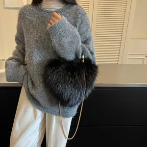 Black fluffy heart-shaped bag with a gold chain strap styled against a gray knit sweater