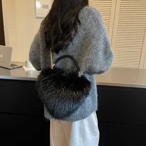 Back view of a woman carrying a black heart-shaped bag with a woven handle and gold chain strap