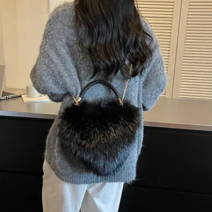 Back view of a black plush bag with a braided handle and gold chain strap, worn over a sweater