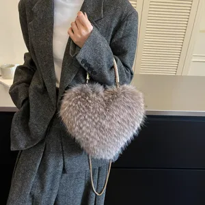 Model holding a heart-shaped bag with soft taupe faux-fur texture and a chain-and-cord strap