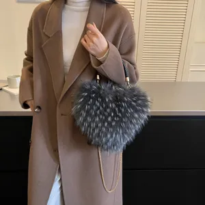 A person carries a fluffy gray heart-shaped handbag with a braided handle and gold chain strap
