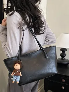 Μαύρη ευρύχωρη τσάντα tote από PU με χερούλια, φορεμένη στον ώμο και με λούτρινο μπρελόκ κούκλας