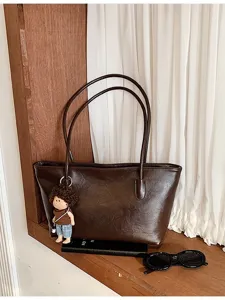 Σκούρα καφέ τσάντα tote από συνθετικό δέρμα, με φερμουάρ, μακριά διπλά χερούλια και κρεμαστό κουκλάκι