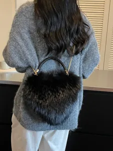 Black fluffy handbag with woven handles and a gold chain strap, shown worn over the shoulder