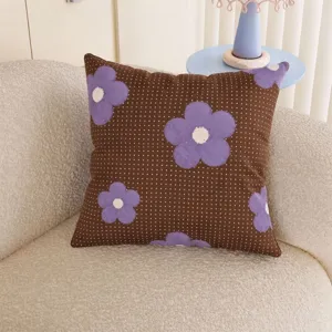Close-up of purple flowers and white dots on a brown fabric cushion in a cozy living room