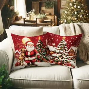 Dos cojines rojos con Papá Noel, un reno, árboles navideños y un pueblo nevado sobre un sofá blanco