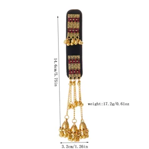 Flat lay of a black velvet ornament with red stones, gold filigree, dangling bells and tassels