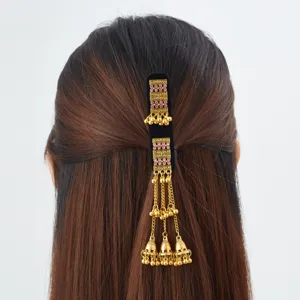 Back view of a black velvet hair clip with pink stones and dangling gold chains and bells
