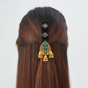 Vue arrière d'un ornement de cheveux avec pierres vertes, clochettes dorées et base en velours noir