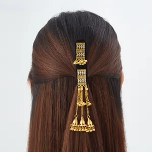 Rear view of dark hair adorned with a black velvet clip, rhinestones, and dangling gold bell tassels
