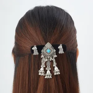 Back view of hair with an ornate silver barrette, turquoise accents and dangling bell tassels
