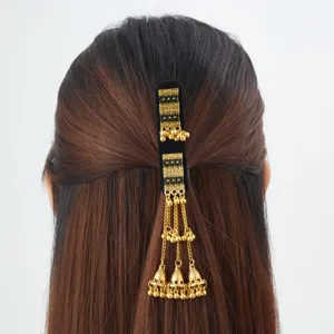 Rear view of dark hair styled with a black velvet barrette, gold chains, and dangling bell charms