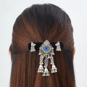Rear view of a silver ornamental hair clip with a blue gem and dangling bell tassels
