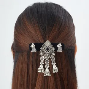 Back view of dark hair with a black barrette, silver filigree centerpiece and dangling bell charms