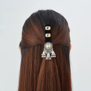 Rear view of a half-up hairstyle with a black velvet clip, crystal accents and silver bell tassels