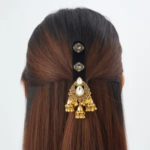Cheveux bruns vus de dos, barrette noire ornée de pendants dorés, pierres blanches et clochettes