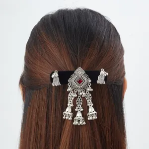 Back view of a black velvet hair clip with silver bells, dangling tassels and a red gem