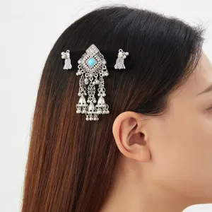 Side view of a silver hair ornament with a blue stone and dangling bell chains worn in dark hair