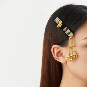 Side view of a black hair clip with colorful stones, gold filigree, chains, and dangling bells