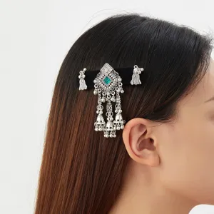 Side view of a model wearing a silver filigree hair clip with a green gem and dangling bell charms