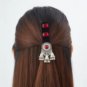 Half-up hairstyle with a black velvet clip, red gems, silver filigree and dangling bell tassels